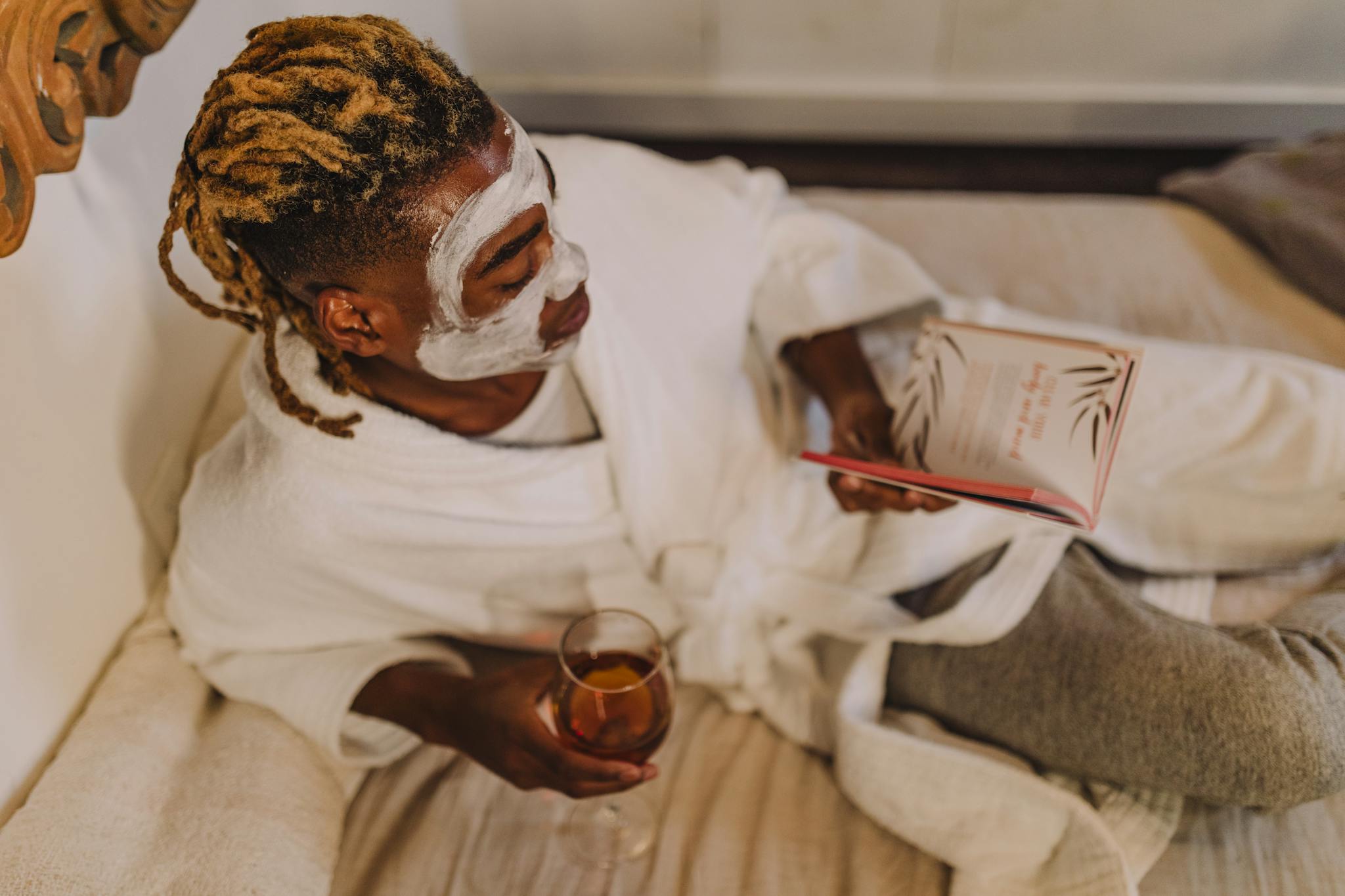 About 5 A person enjoying a spa day with a facial mask, book, and wine, embodying relaxation.
